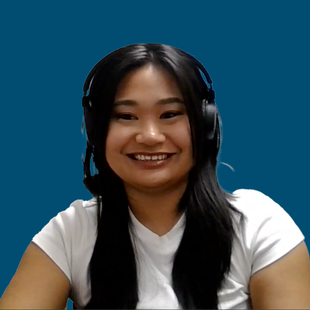 A person with long dark hair, wearing a white shirt and a headset, smiles in front of a solid blue background.